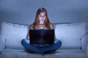 Image of shocked girl using facebook at night